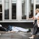 Two women walk past a person lying on the pavement in London, 28 July