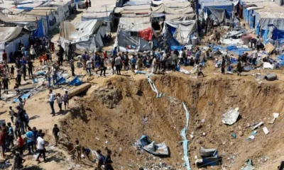 Palestinians inspect the site of an overnight Israeli strike on a medicine warehouse next to tents sheltering displaced families in Deir el-Balah, in central Gaza, on 1 August 2026. There is a huge crater in the earth.