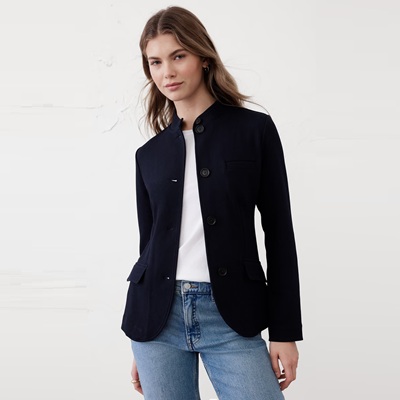 A woman wearing blue jeans, a white top, and navy blazer