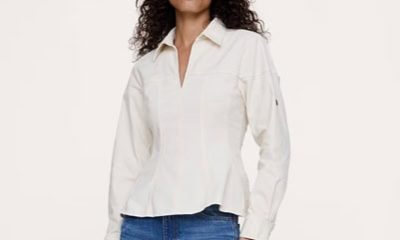 A woman wearing a beige button-front blouse and medium blue jeans
