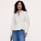 A woman wearing a beige button-front blouse and medium blue jeans