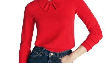 A woman wearing a red bow-neck sweater and dark blue jeans