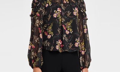A woman wearing black pants and a black floral blouse