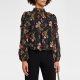 A woman wearing black pants and a black floral blouse