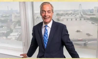 Nigel Farage of Reform UK posing against an internal window frame, smiling