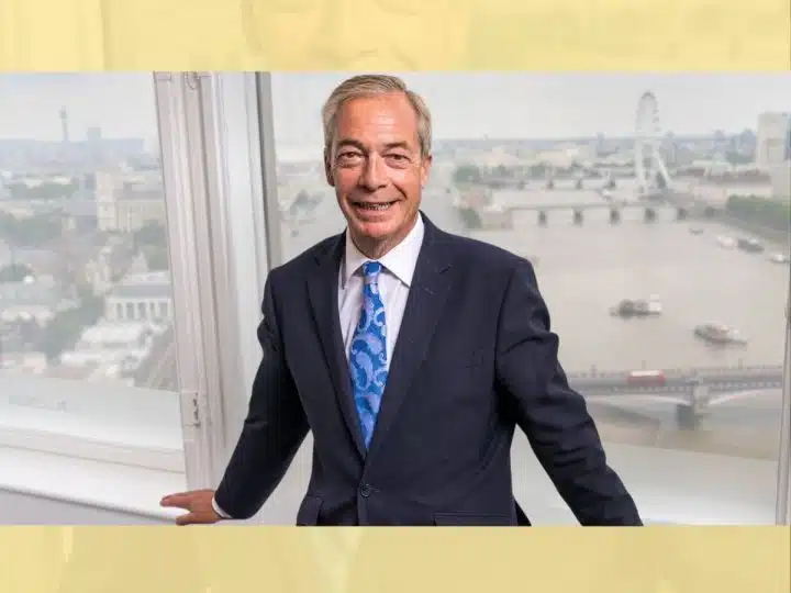 Nigel Farage of Reform UK posing against an internal window frame, smiling