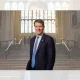 Richard Tice of Reform UK photographed on the Parliament estate in a large open room with steps and a large window behind him