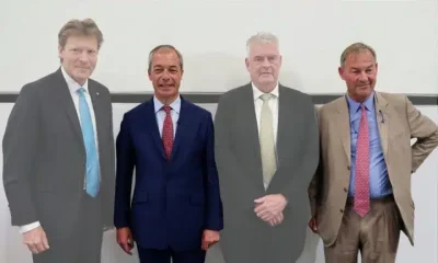 Rupert Lowe of Restore Britain and Nigel Farage of Reform UK standing with other politicians in a line for a photo op