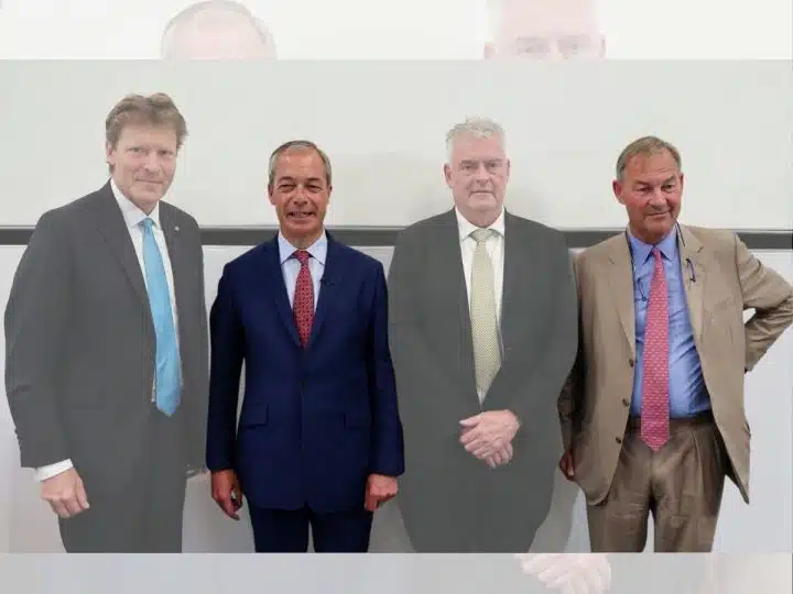 Rupert Lowe of Restore Britain and Nigel Farage of Reform UK standing with other politicians in a line for a photo op