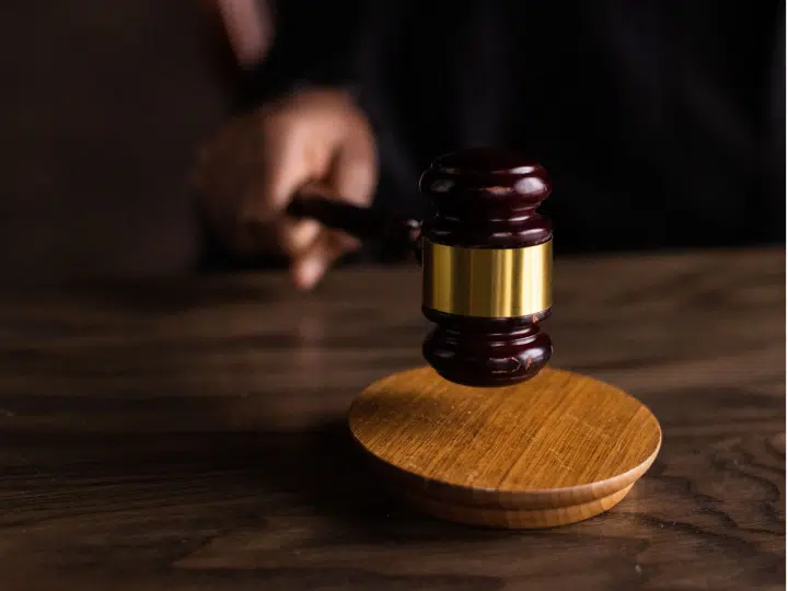 A hand holds the end of a court gavel to visualise the German court story