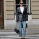Diane Batoukina wears black large sunglasses from Chanel, a white ribbed tank-top from Anine Bing, a black shiny leather blazer jacket, blue faded denim flared pants, a black shiny grained leather Timeless handbag from Chanel, black shiny leather pointed heels mules, during a street style fashion photo session, on April 07, 2023 in Paris, France.