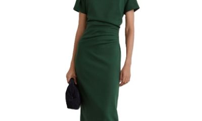 A woman wearing a dark green midi dress, carrying a black handbag