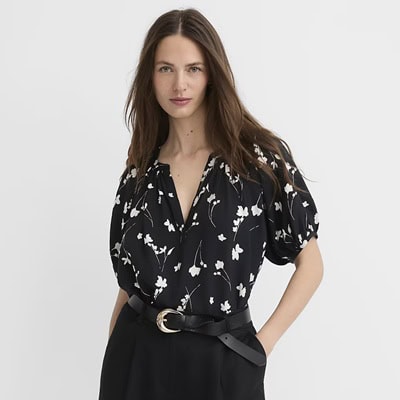A woman wearing black shorts, a black belt, and a black-and-white floral top