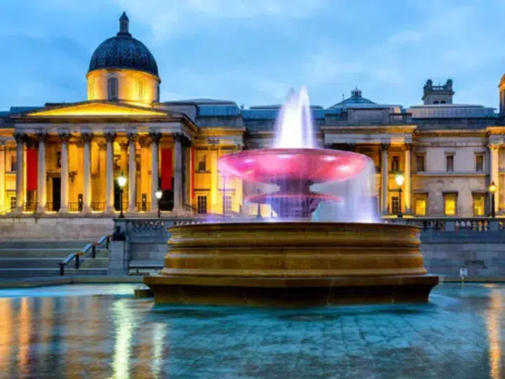 Outside the National Gallery in London in the evening when it's illuminated with lights and so is the large water fountain outside. Workers are experiencing racially divided break facilities at the historic institution