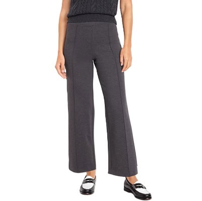 A woman (bottom half shown) wearing a gray vest, gray pants, and black-and-white loafers