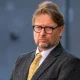Professor David Miller in a smart suit and bright tie looking stern in 2023 outside the centre where his tribunal hearing was taking place