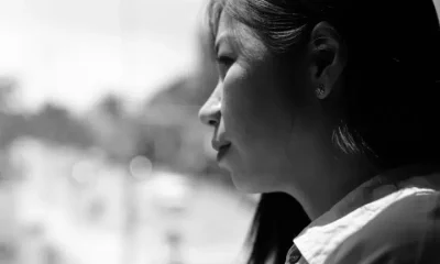 A black and white portrait of a woman gazing out of a window, capturing reflection and contemplation, in relation to the autism strategy story