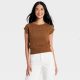 A woman wearing a short-sleeve brown sweater and white pants