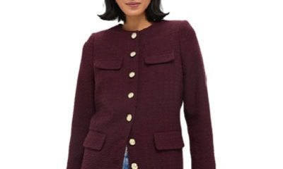 A woman wearing a wine-colored jacket with gold buttons, and light blue jeans