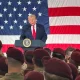 President Donald Trump speaks to beret-wearing US military soldiers infront of a large American flag at Fort Bragg, North Carolina on Friday, 13 February 2026
