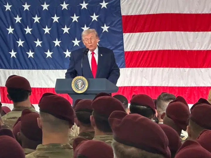 President Donald Trump speaks to beret-wearing US military soldiers infront of a large American flag at Fort Bragg, North Carolina on Friday, 13 February 2026
