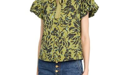 A woman wearing blue button-fly jeans and a green/black/blue floral top