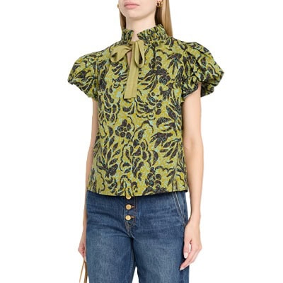 A woman wearing blue button-fly jeans and a green/black/blue floral top