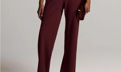 A woman (bottom half of body shown) wearing burgundy pants, a matching top, and sandals