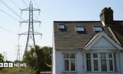 A white painted house with a line of electricity pylons beside it