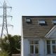 A white painted house with a line of electricity pylons beside it