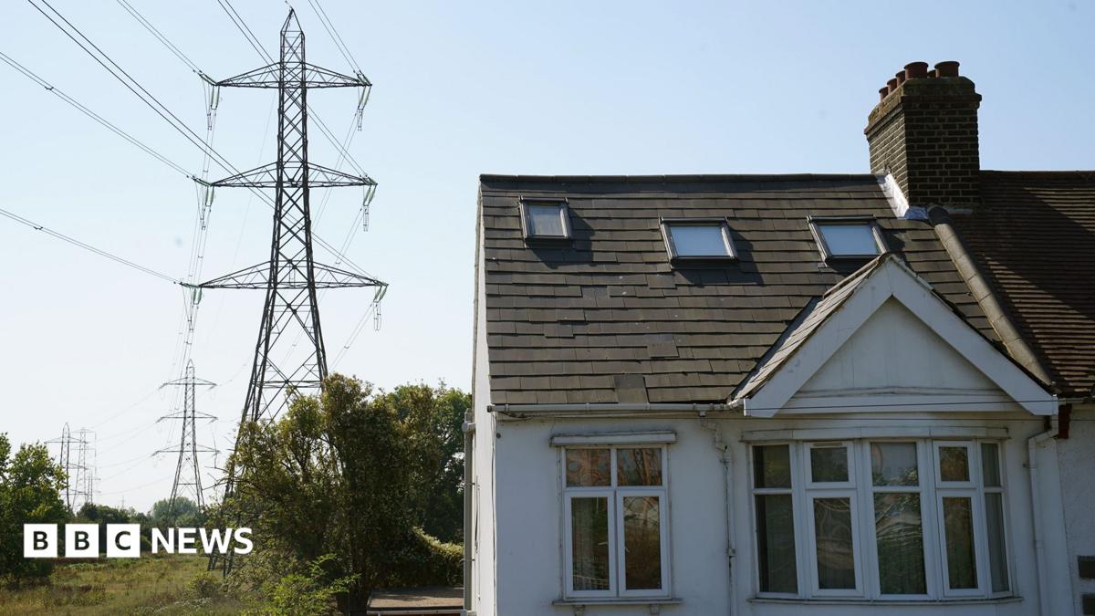 A white painted house with a line of electricity pylons beside it