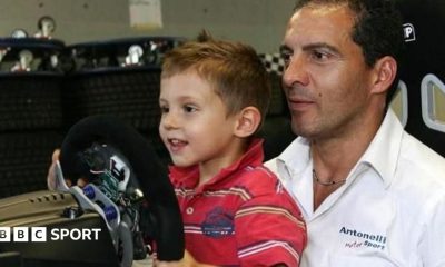 A young Kimi Antonelli sitting in a go-kart while wearing racing overalls and a racing helmet