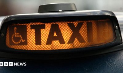 Hackney carriage or London taxi ("Black Cab") waits on the cab rank. An illuminated orange sign which reads 'TAXI'.