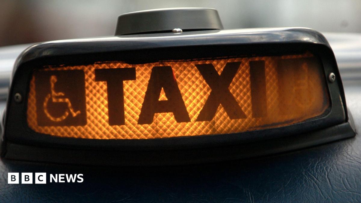 Hackney carriage or London taxi ("Black Cab") waits on the cab rank. An illuminated orange sign which reads 'TAXI'.