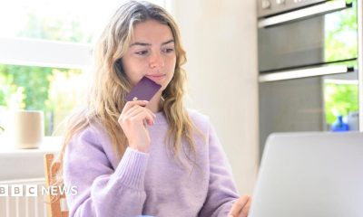 A young woman sitting at her laptop while holding a credit card