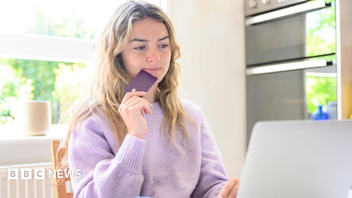 A young woman sitting at her laptop while holding a credit card