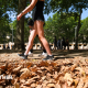 A woman in shorts and trainers walks through fallen leaves amid a UK heatwave