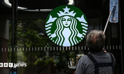A cleaning lady wipes the window of a Starbucks coffee shop
