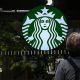 A cleaning lady wipes the window of a Starbucks coffee shop