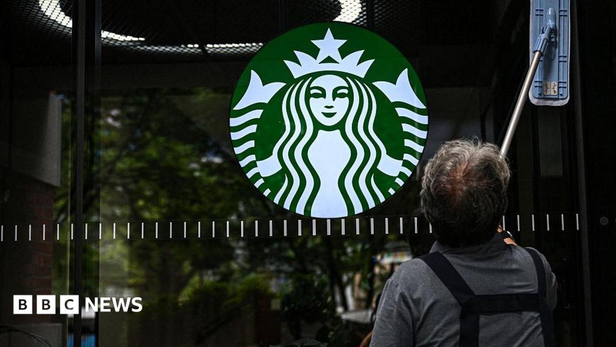 A cleaning lady wipes the window of a Starbucks coffee shop