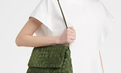 woman wears white dress with weirdly large sleeves and a green suede leather bag that is gorgeous although probably leaving marks on her dress