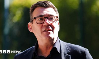 Andy Burnham wearing a dark suit and glasses.