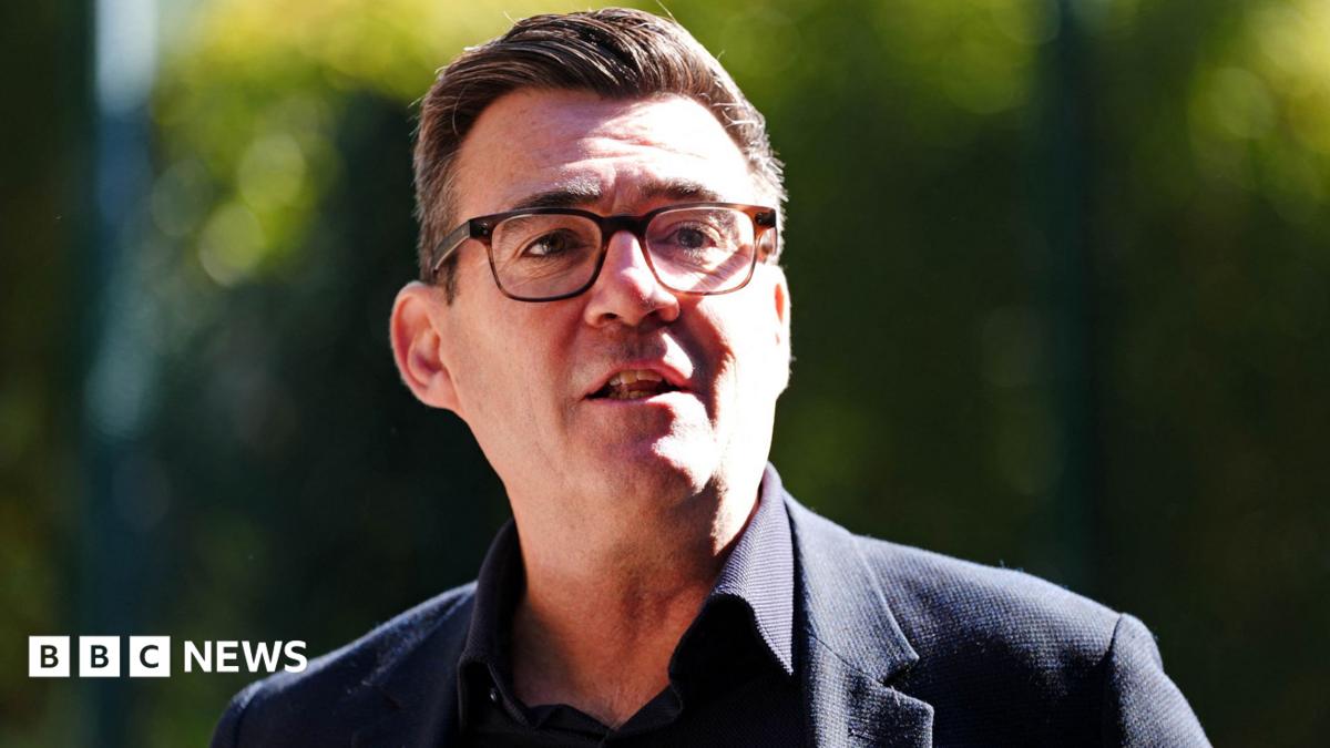 Andy Burnham wearing a dark suit and glasses.