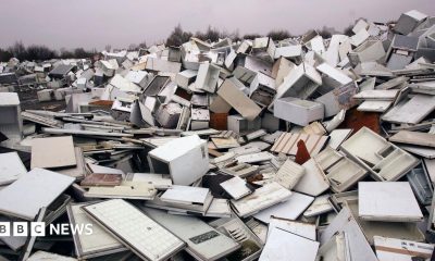 A huge pile of broken fridges is pictured, with white doors removed from some units.