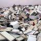 A huge pile of broken fridges is pictured, with white doors removed from some units.