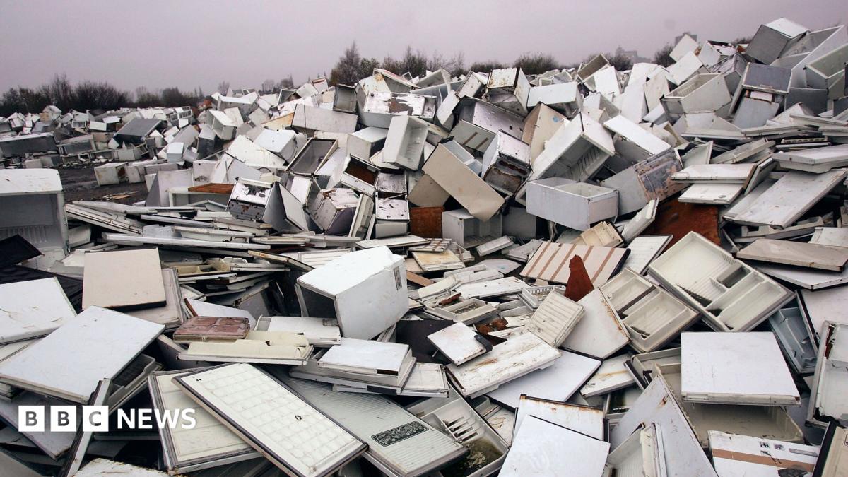 A huge pile of broken fridges is pictured, with white doors removed from some units.