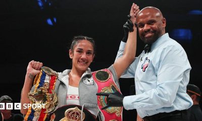 Amanda Serrano has her arm raised by a referee and is celebrating with her belt