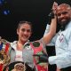 Amanda Serrano has her arm raised by a referee and is celebrating with her belt