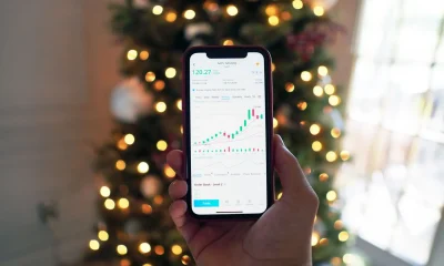 A person holding a smartphone displaying a stock market chart for AAPL on the NASDAQ exchange
