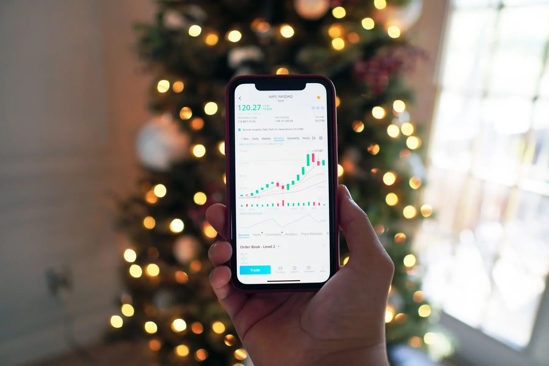 A person holding a smartphone displaying a stock market chart for AAPL on the NASDAQ exchange